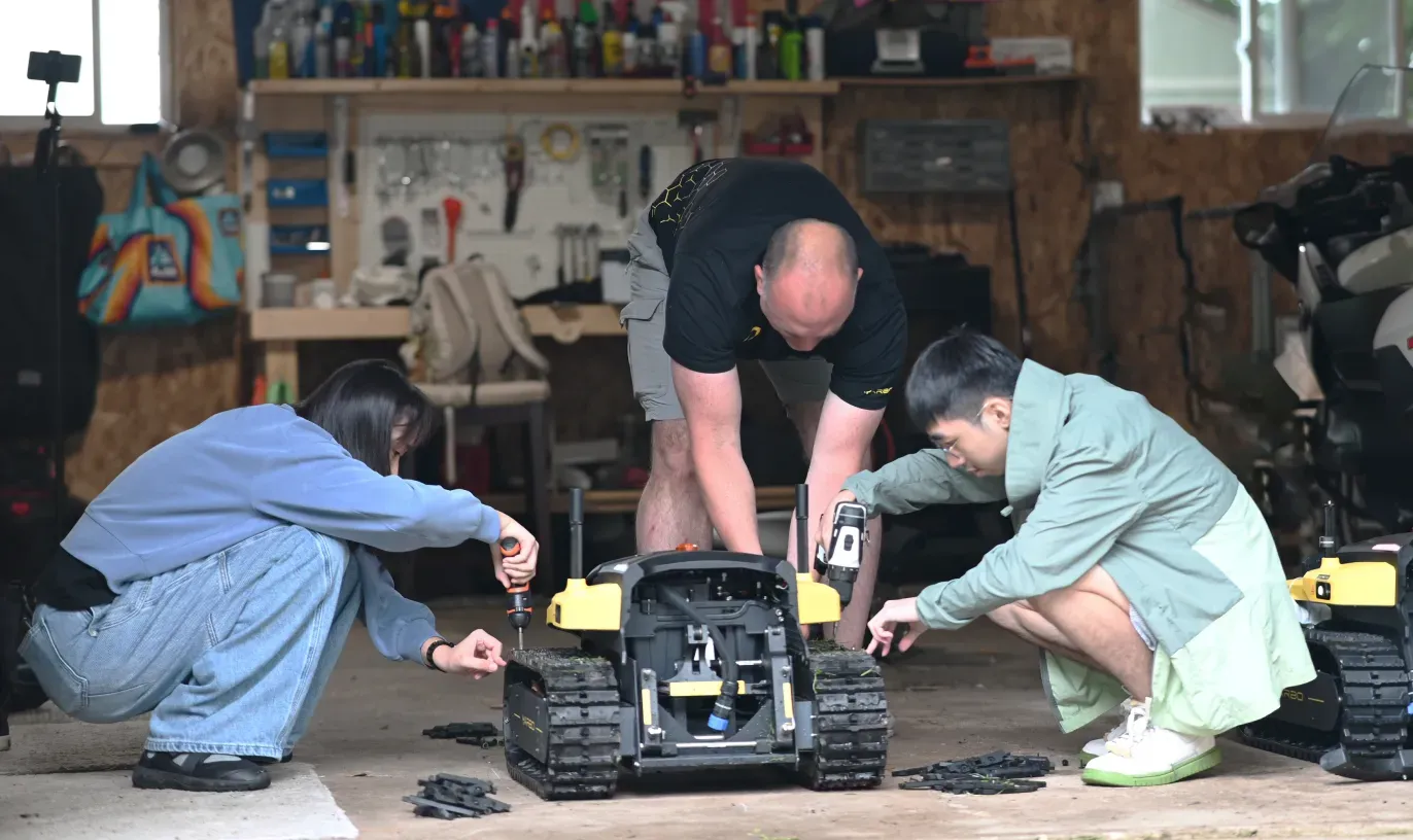 Three Zippy crew members working together on a Yarbo Core in the workshop