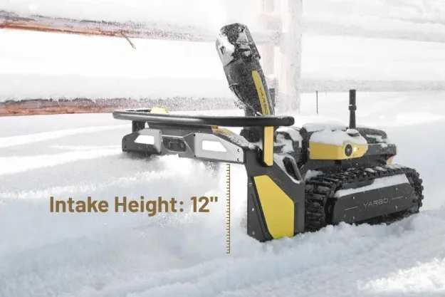 The robot working through deep snow beside a fence, labeled with its 12-inch intake height